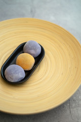 Fototapeta na wymiar Japanese Mochi in rice dough and on a beautiful bamboo plate and concrete background. Traditional Japanese dessert.