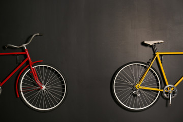 Fototapeta na wymiar Color bicycles hanging on black wall indoors