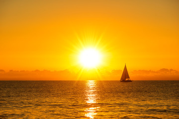 A sailboat sailing with the sunrise sun