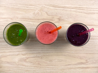 Glass with three smoothie and straw, on the kitchen, top view