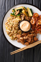 Hibachi fried rice with egg, shrimp, steak and vegetables close-up in a plate. Vertical top view