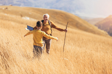 Senior man with grandson on country walk in autumn.