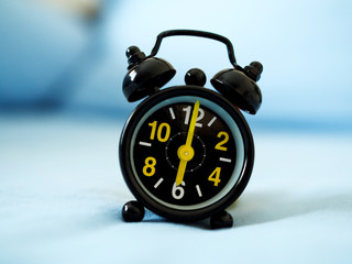 vintage black alarm clock on bed.