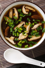 portion of Japanese soup with shiitake mushrooms and green onions close-up in a bowl. Vertical top view