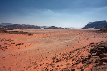Fototapeta na wymiar Panoramic view of rocky mountains and red sand in the Jordanian desert of Wadi Rum.