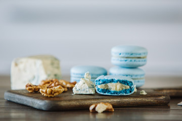 Raw walnuts with a broken macaron on wood board