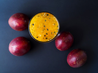 Top view of glass drink with yellow passion fruit juice and black seeds, fresh fruit juice in summer isolated on dark background.