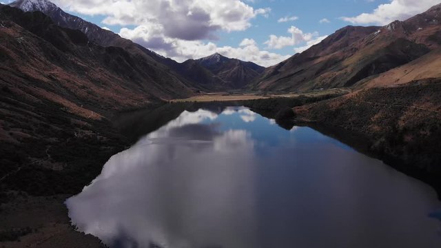 descend reveals reflection of clouds and mountains at epic golden mountain scenery in 4k