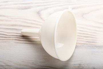 White plastic funnel liquid on wood kitchen table background.