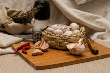 garlic solo in a wicker basket on a wooden Board on a linen background. next to the knife, press, pepper