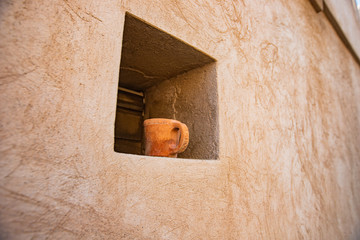 a clay pot in the window opening of a house in Oman