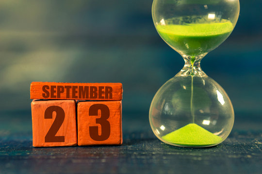 september 23rd. Day 23 of month,Handmade wood cube with date month and day and hourglass with green sand. Time passing away. artistic coloring.  autumn month, day of the year concept