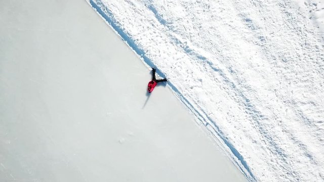 aerial footage, perspective, birds eye view, guy layed in the ice/snow