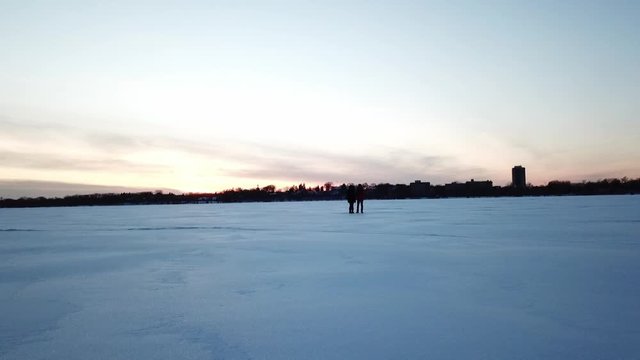 winter landscape two person standing on a frozen lake during blue hour