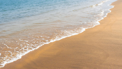 Panorama of long surf waves on the coast.   Sand beach background. Beautiful view of tropical ocean beach with long blue waves rolling. 