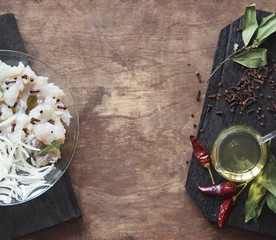 XE salad of freshly salted river pike fish on a cutting kitchen board with ingredients for cooking. Pike fillet pieces. Wooden brown background.
