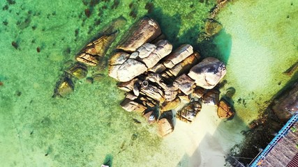 Pile of beautiful limestone cliffs on shallow lagoon with coral reefs under crystal emerald water near exotic beach in Thailand