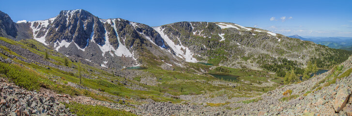 Fototapeta na wymiar Large panorama of the mountain landscape. Large panorama of the mountain landscape. Valley with lakes, spring greens and snow on the rocky slopes.