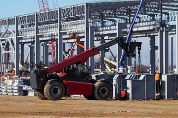 Telescopic handler at work in a large construction site. Intense building activity on background  © luca piccini basile