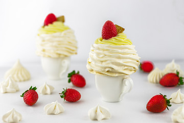 Pavlov’s (pavlova) cakes with strawberries, on a white cup, white background, high key