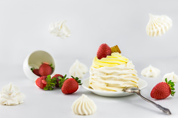 Pavlov’s (pavlova) cake with strawberries, on a white saucer, vintage spoon, strawberries falling from a white cup, next to meringues, meringues fly, white background, high key