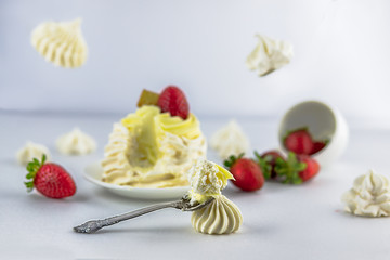 Pavlov’s (pavlova) cake with strawberries, on a white saucer, vintage spoon, strawberries falling from a white cup, next to meringues, meringues fly, white background, high key