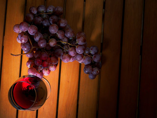Still life, glass of red wine and red grapes on a wooden table. Warm tone. Top view.