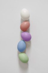 Five multicolored easter eggs lie in a straight line. White background for lettering and design. Copy space for your text
