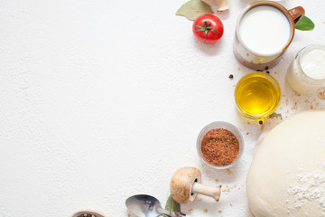 Ingredients for cooking on a white background, including milk, eggs, spices and dough with olive oil and black pepper in polka dots, with copy space. The concept of cooking and recipes.