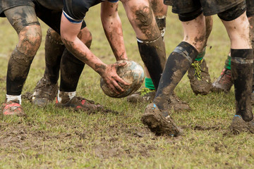 Dirty hands holding a rugby ball in a rugby game - Powered by Adobe