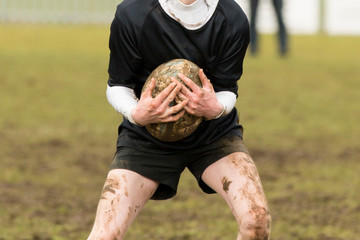 Dirty hands holding a rugby ball in a rugby game
