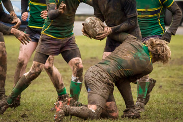Dirty hands holding a rugby ball in a rugby game - obrazy, fototapety, plakaty