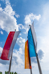 Die Flaggen von Deutschland, Bayern und Unterfranken wehen im Wind vor weißblauem Himmel