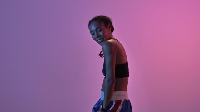 Happy african sports woman dancing and looking at the camera isolated led flashlights background