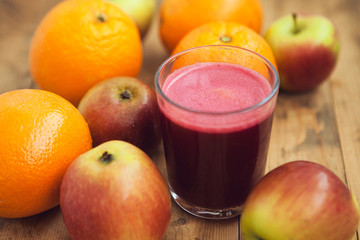 Glass with juice and fruits: apples and oranges