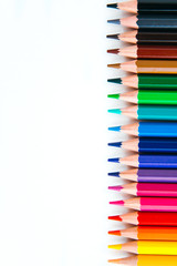bright multi-colored flat lay pencils for drawing on a white background, place for text 