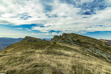 moody highland rocky mountain landscape dry grass ground and cloudy blue sky background scenic view