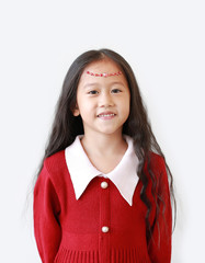 Portrait of pretty little girl in scarlet red dress with Crystals on forehead and smiling over white background.