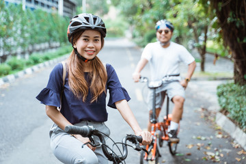 Fototapeta na wymiar asian young couples wearing helmets enjoy riding bikes together on trips in the park