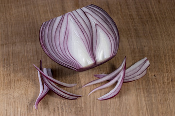 Red onion is cut in half and lies on a white oak kitchen board, with artificial lighting. Still...