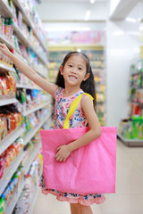 Cute Asian little girl carrying a pink recycle bag (spun ball bag) while go to supermarket. Reuse and reduce global warming concept.