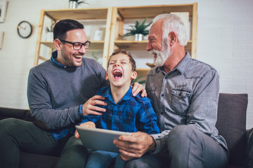 Portrait of a three generation family spending time together at home using digital tablet.