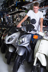Fototapeta na wymiar serious man motorcyclist choosing the bike in the shop