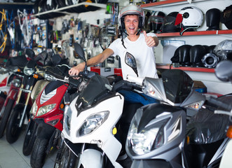 Fototapeta na wymiar Cheerful man in helmet is sitting on motorbike satisfied by purc
