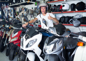 Fototapeta na wymiar Man in helmet is sitting on motorbike satisfied by purchase