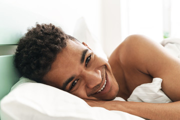 Fototapeta na wymiar Smiling young african guy in the morning in bedroom
