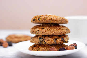 Fresh oatmeal friable cookies on a plate with nuts and raisins. The concept of a delicious and healthy breakfast.