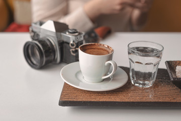 Curly haired photographer woman is resting in a cafe and drinking Turkish coffee