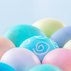 Colorful Easter eggs dyed by colored water isolated on a pale blue background, design concept of Easter holiday activity, close up, copy space.