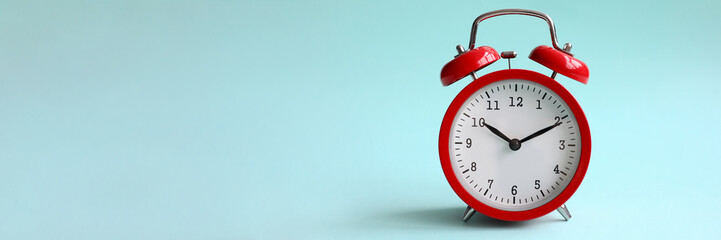 Red alarm clock on turquoise background shows 10 hours 10 minutes in evening or morning. Time to...